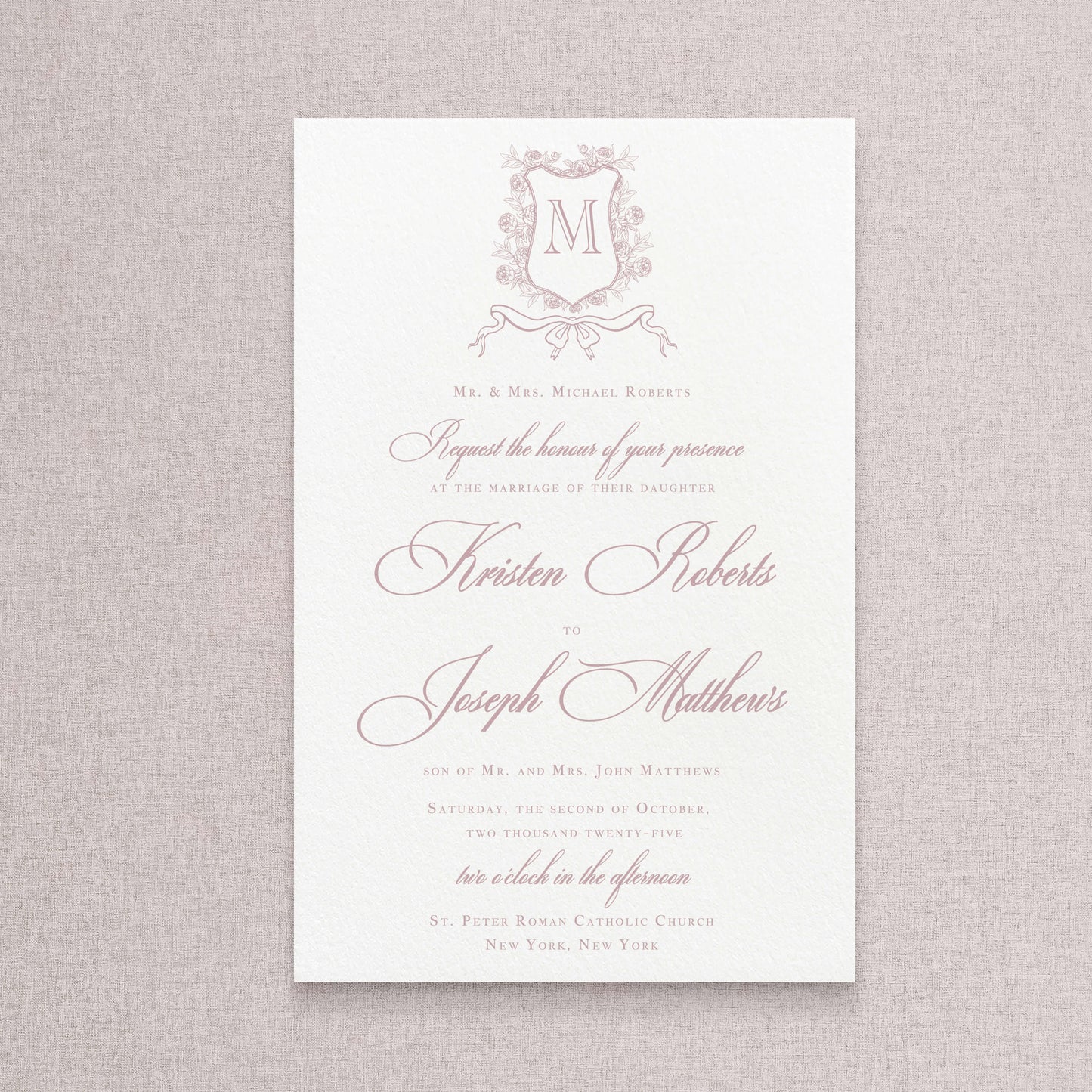 Classic wedding invitation with a floral monogram crest. The ink color is mauve.