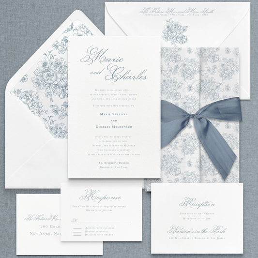 Dusty Blue wedding Invitation Suite shown with floral pattern envelope liner, matching floral pattern vellum jacket, and dusty blue silk ribbon