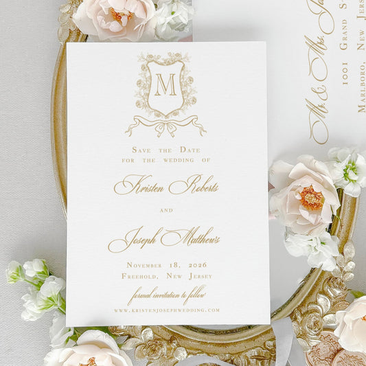 Classic Save the Date Card for Wedding shown  with an elegant floral monogram crest artwork, gold ink, classic script and text fonts.